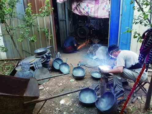 章丘一家生产手工铁锅的厂房内，铁匠师傅们在锻造铁锅
